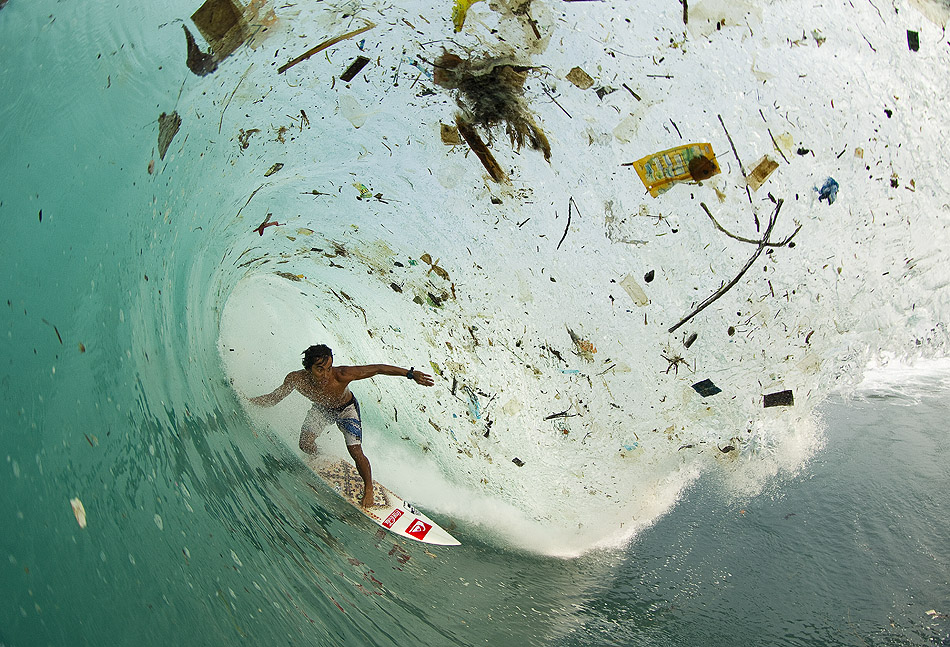 Surfer Dede Suryana riding a wave of (human) trash in Indonesia. Photo by Zak Noyle